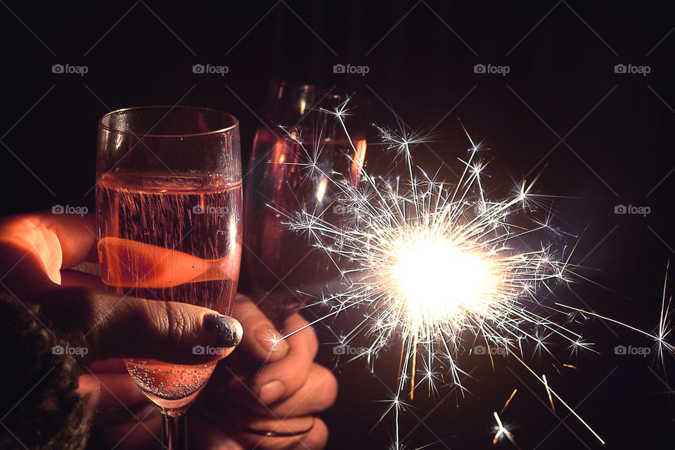 Person holding sparkler and glass