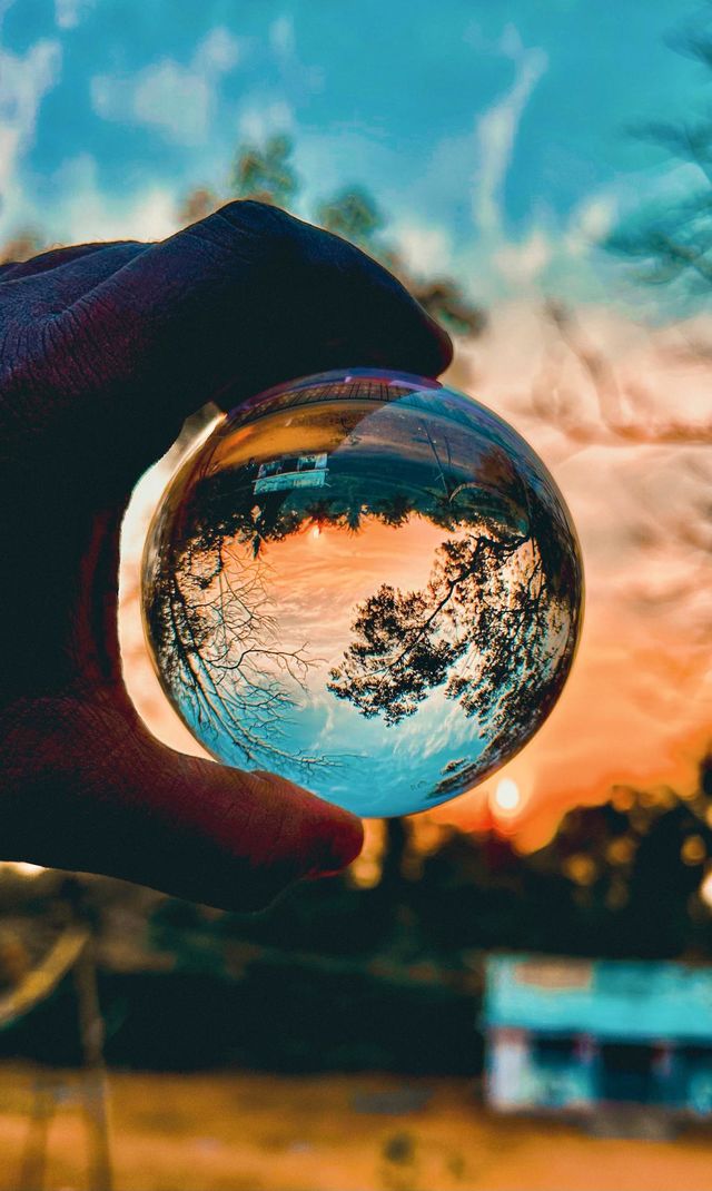 A reflection of sunset sky and sun through the lens ball 