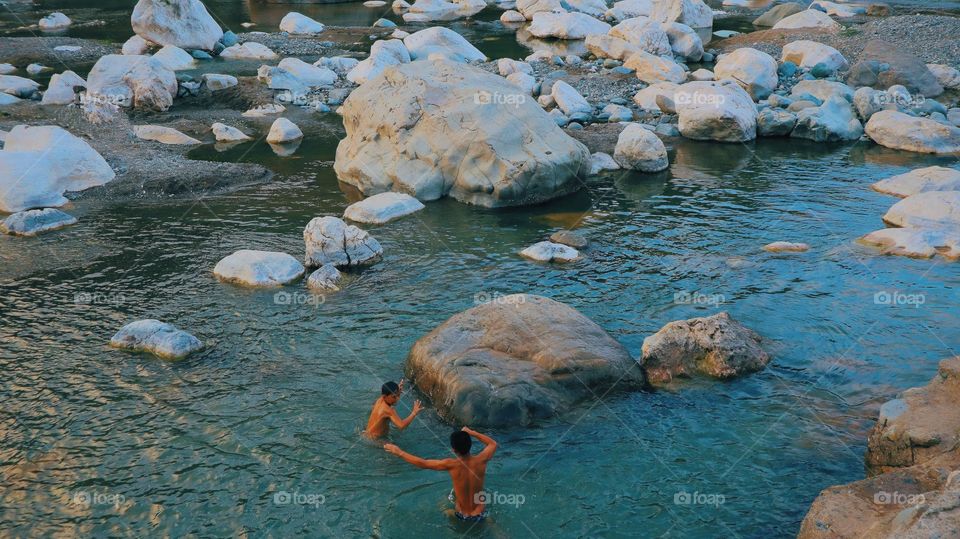 Two boys swimming in the blue lagoon.