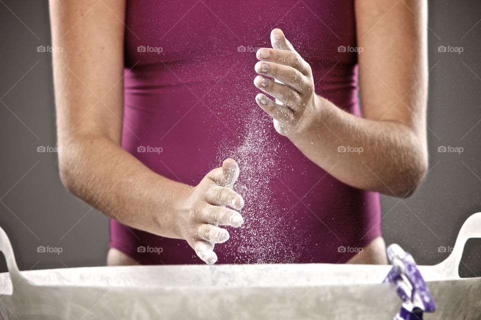 Gymnast preparing to do gymnastics event by chalking hands. 