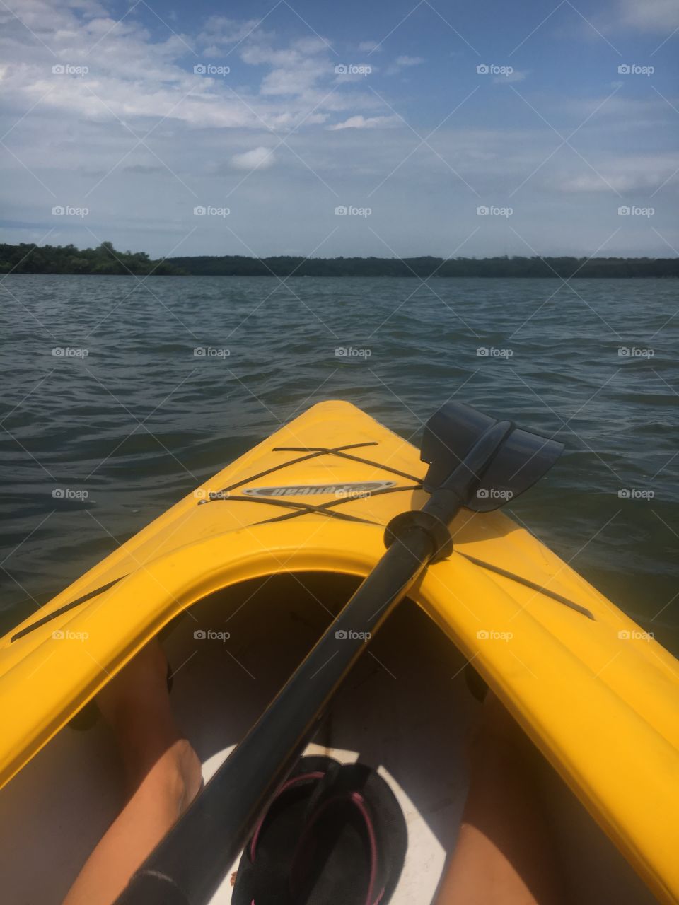 Kayaking a big, dark lake with a yellow kayak, oar is visible