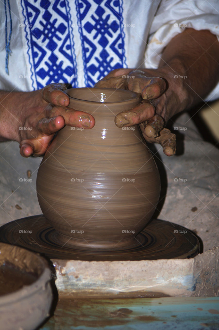 man makes a jug out of clay.