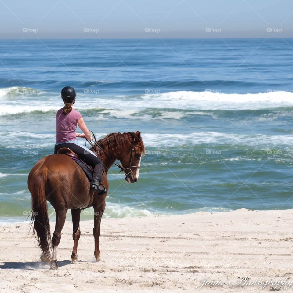 Woman riding horse at beach