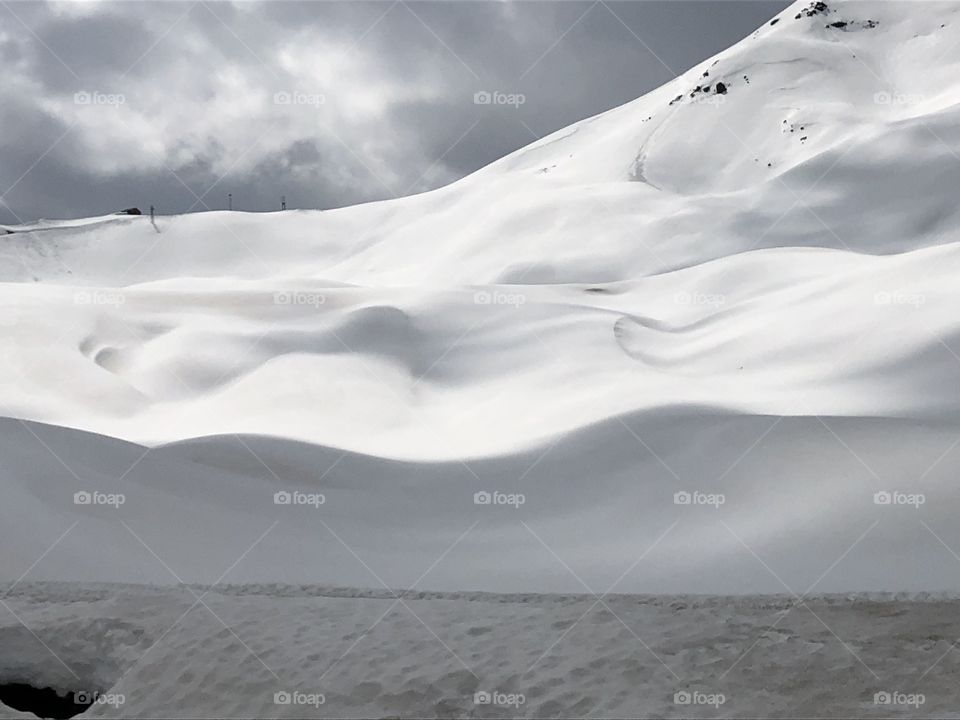 Snowed landscape on Alps in winter time under a cloudy sky