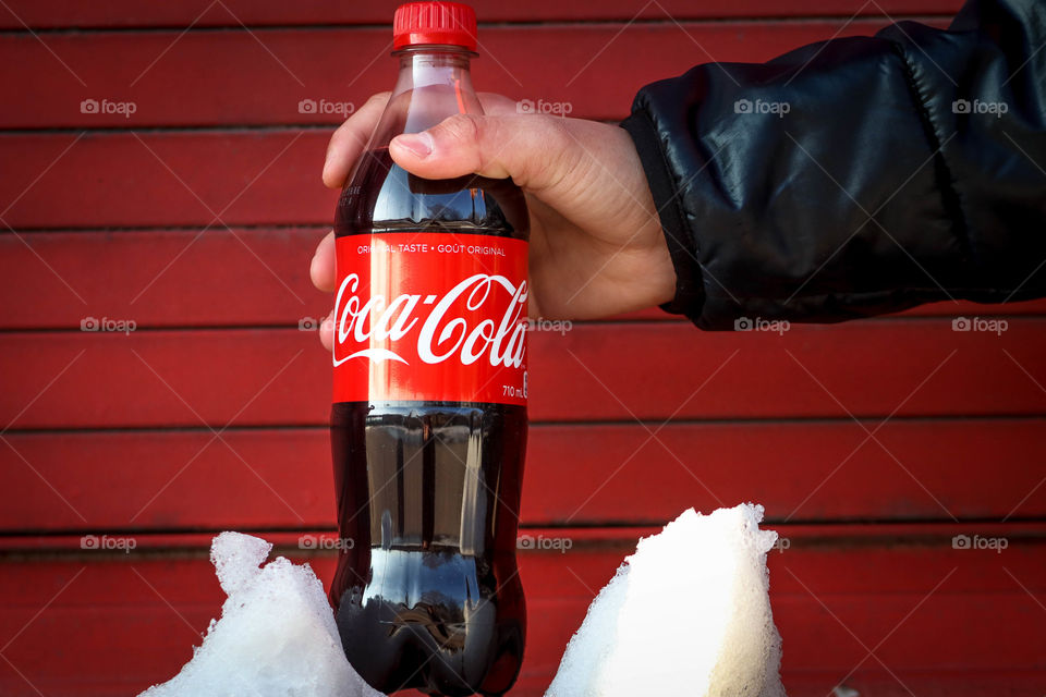 Man's hand holding a bottle of a Coca-Cola