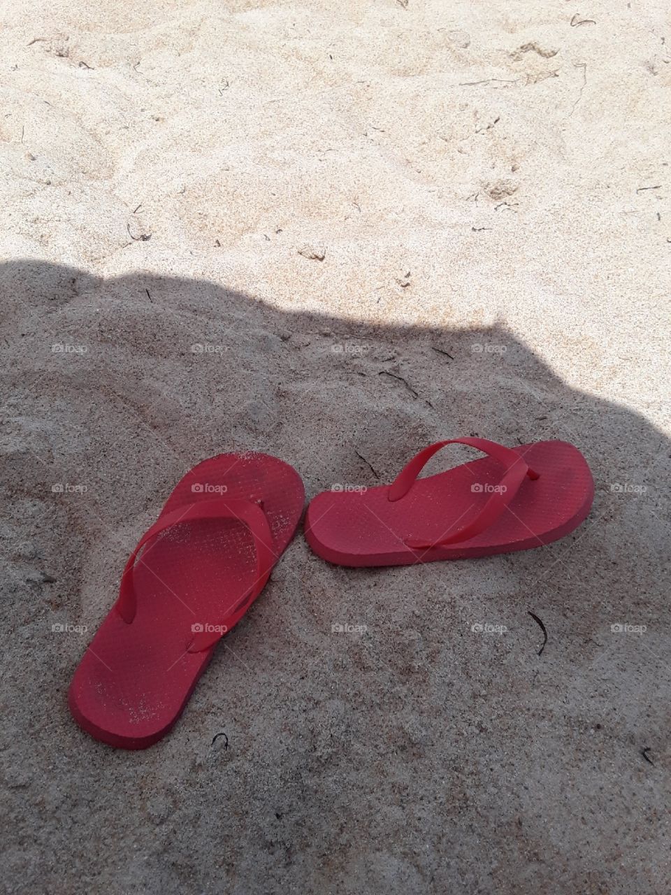 Red flip-flop and sandy beach.