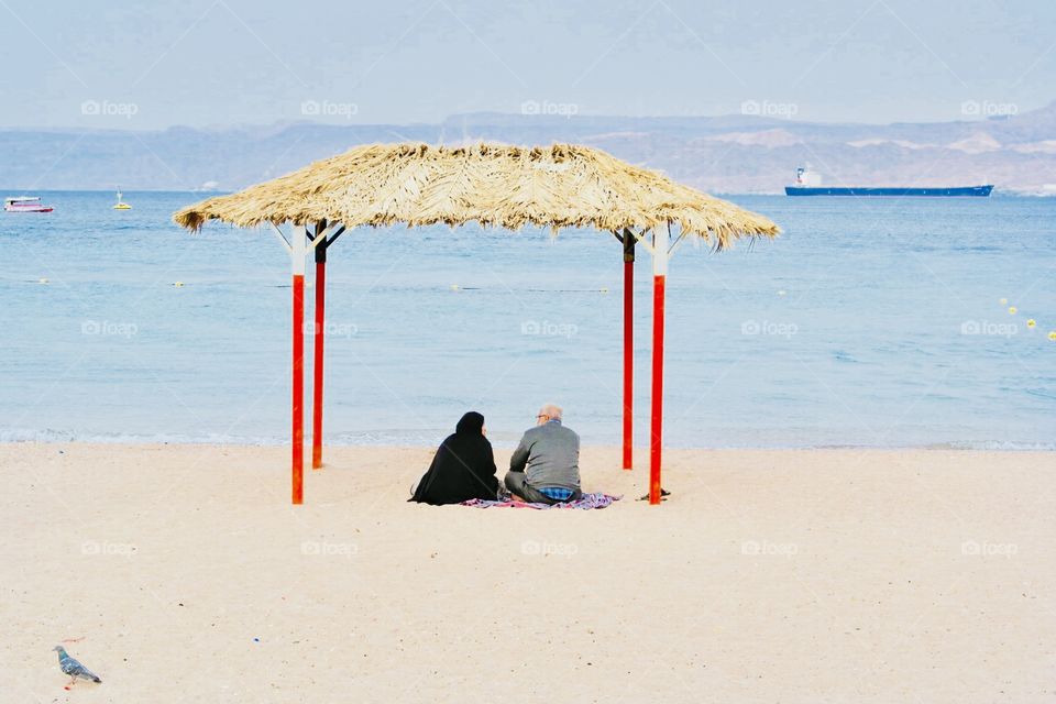A couple sitting in the shelter on the beach