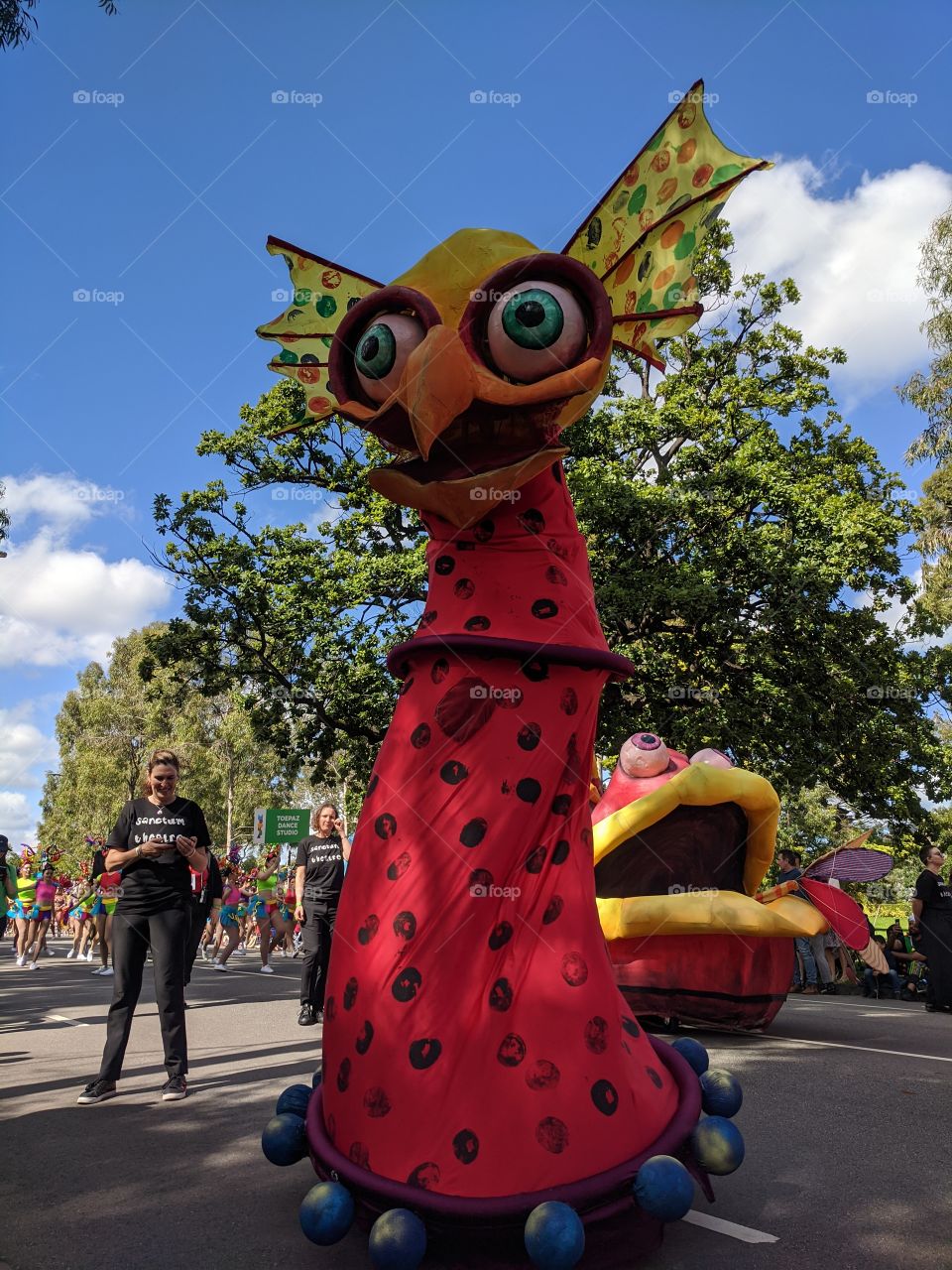 Colourful tall creature parading down the street