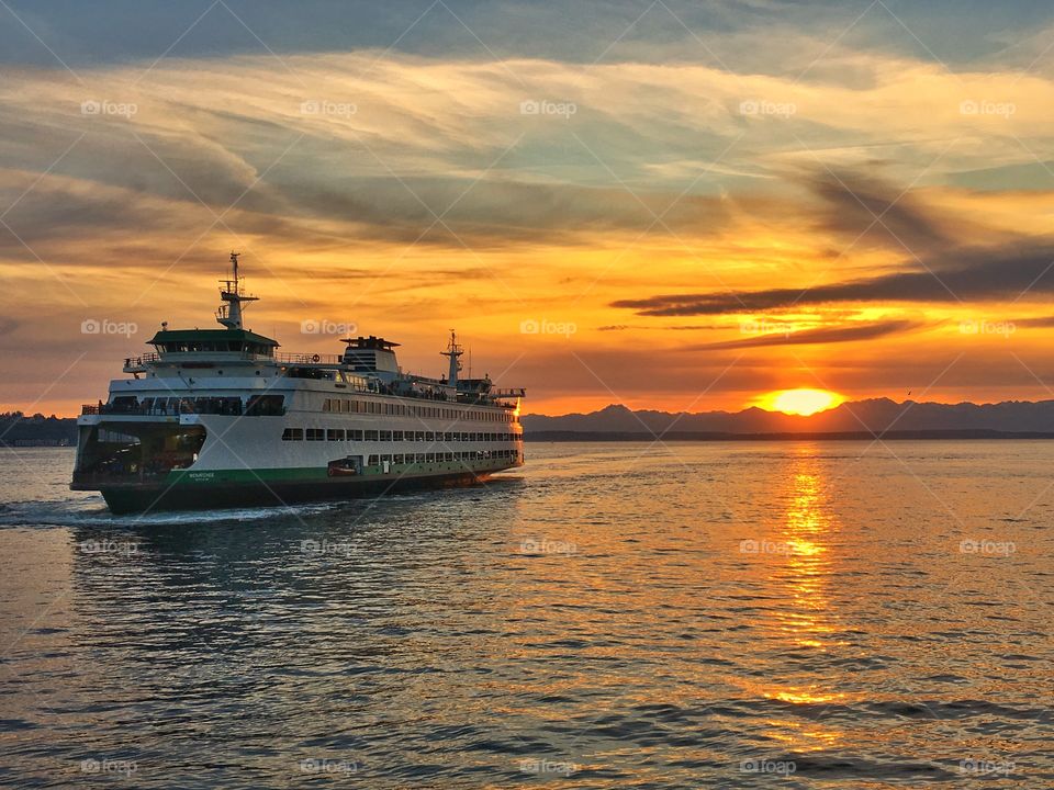 Bainbridge Island to Seattle Ferry with the sun setting over the Olympic Mountains and the rays reflecting off of Puget Sound