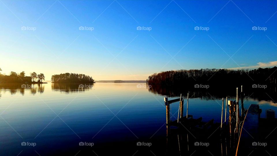 sun rising, lightening the sky over the lake.