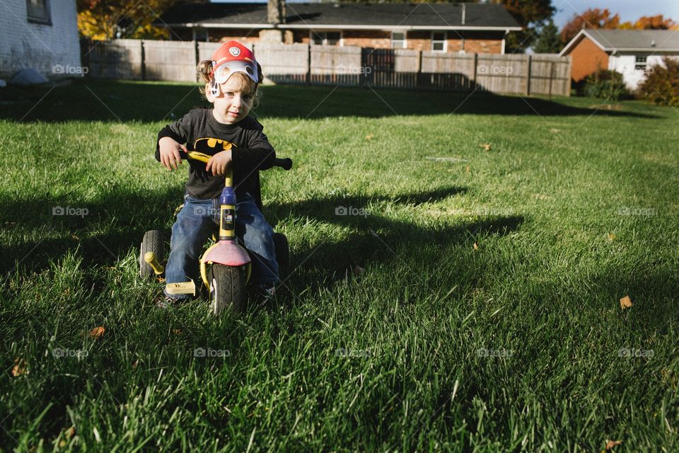 Boy riding tricycle in grass . Tough looking toddler riding tricycle in a grassy back yard