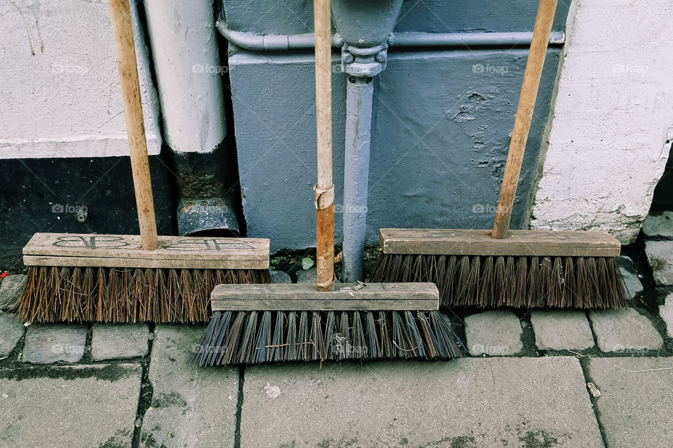 Three brooms standing on the street