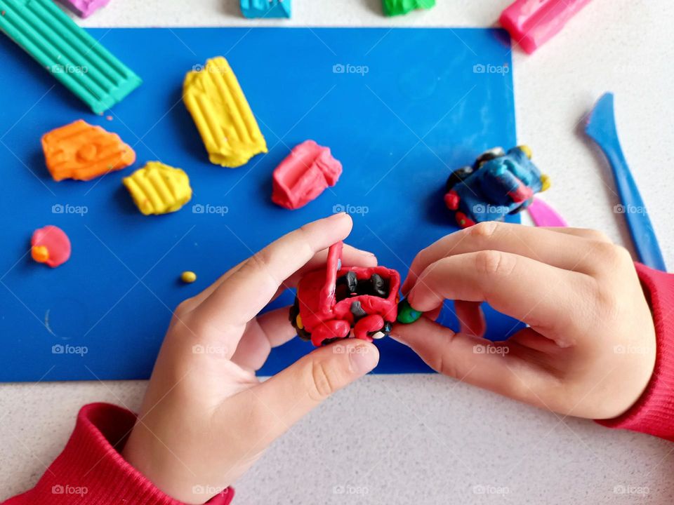 a child sculpts a car from plasticine.