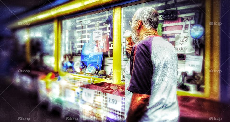 Ice cream. Man eating an ice cream walking along the sea front promenade of an English tourist seaside resort town on a hot day
