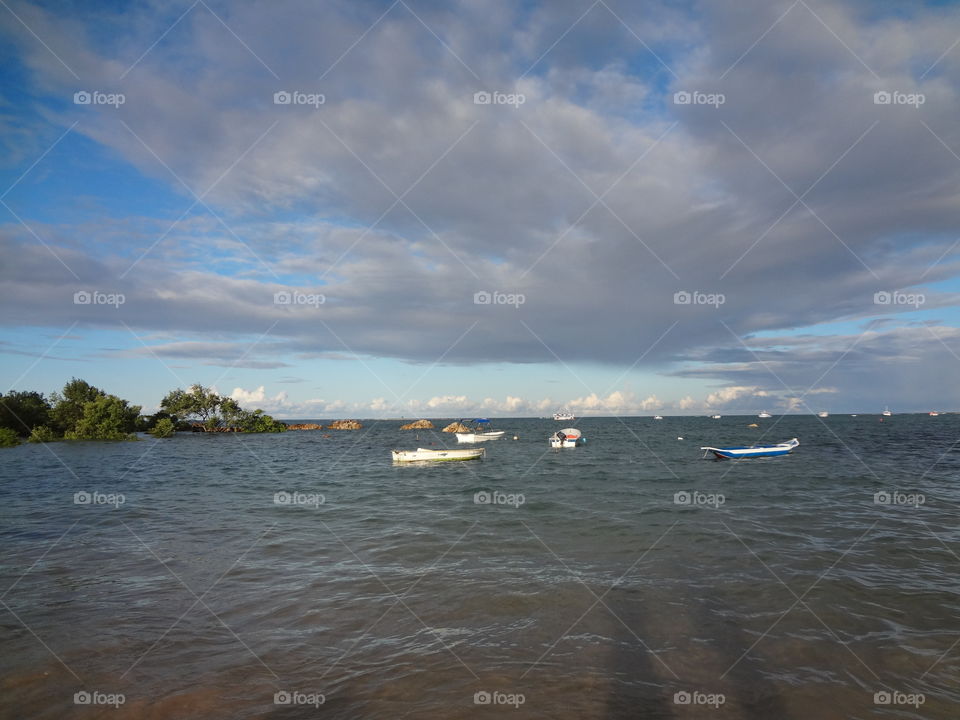 Boats on the ocean in a cloudy blue sky