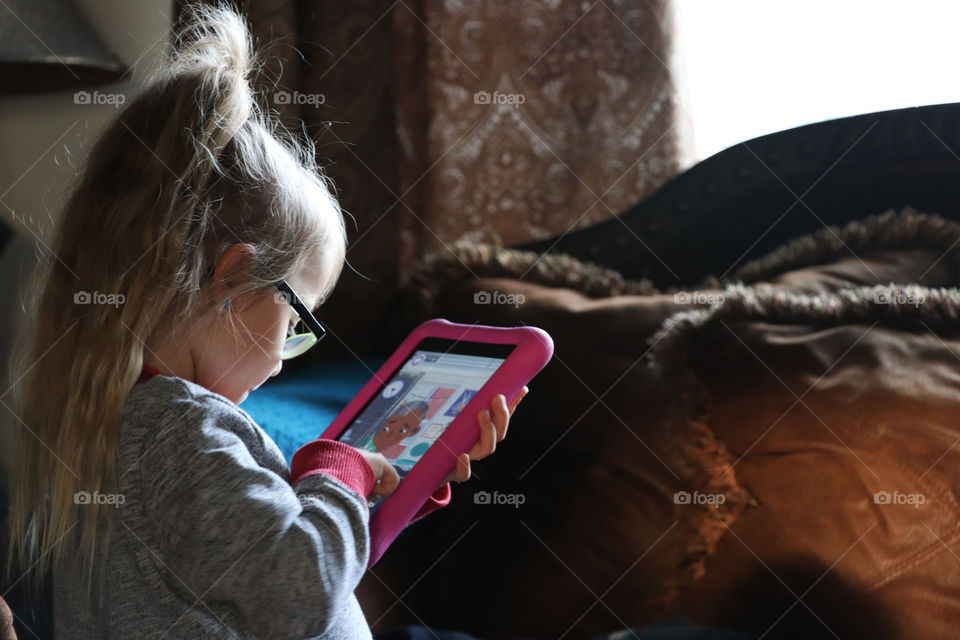 Little girl playing on a tablet