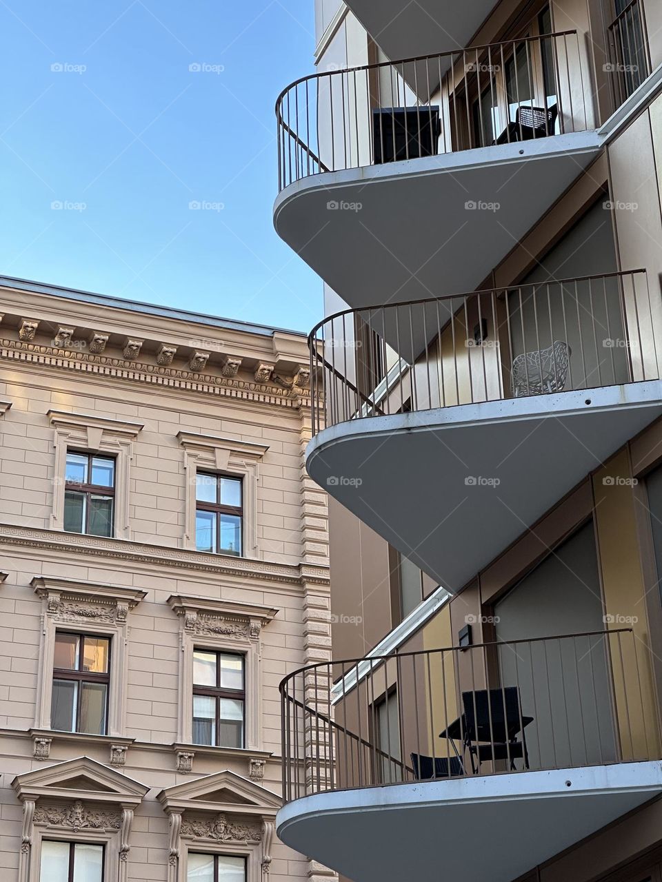 Old vs. new: modern building with triangle balconies against a background of a classical old building. 