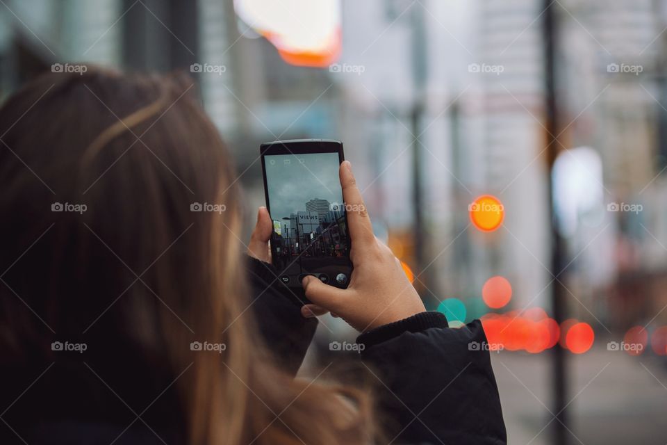 A young woman taking city pictures on her phone