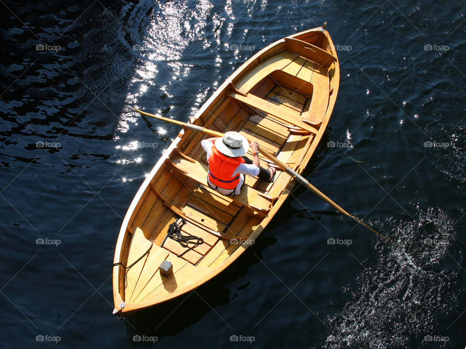 Person rowing wooden boat in lake