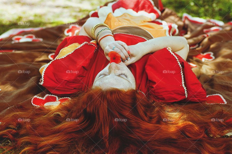 Close up portrait of beautiful young redhead woman,  girl relaxing, dreaming in summer park. Curly red hair. Lifestyle people