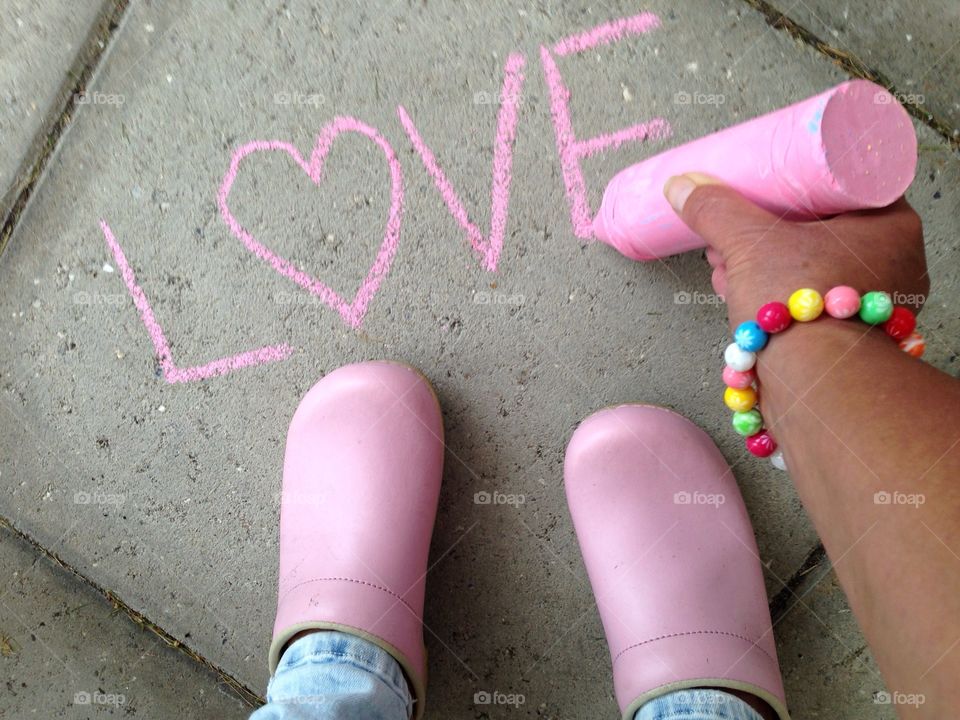 Girl drawing with pink chalk on tiles