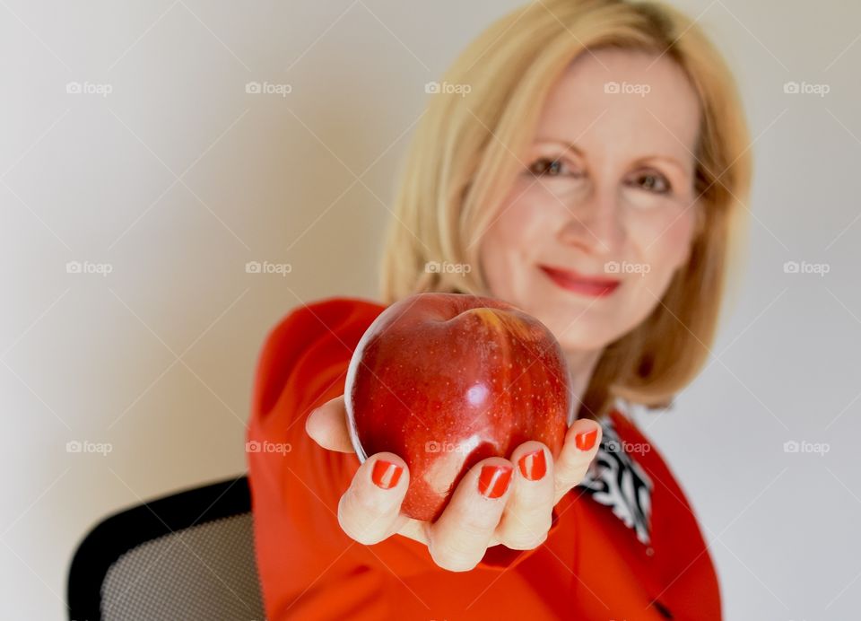 Woman in a red suit holding a red Apple 