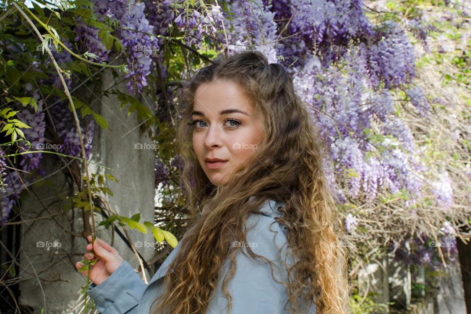 Portrait of a Beautiful Young Girl on Background of Purple Flowers