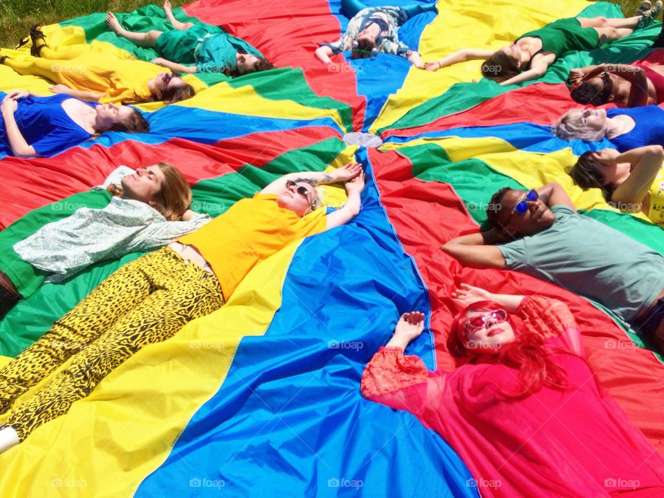 Group of people lying on multicolored parachute