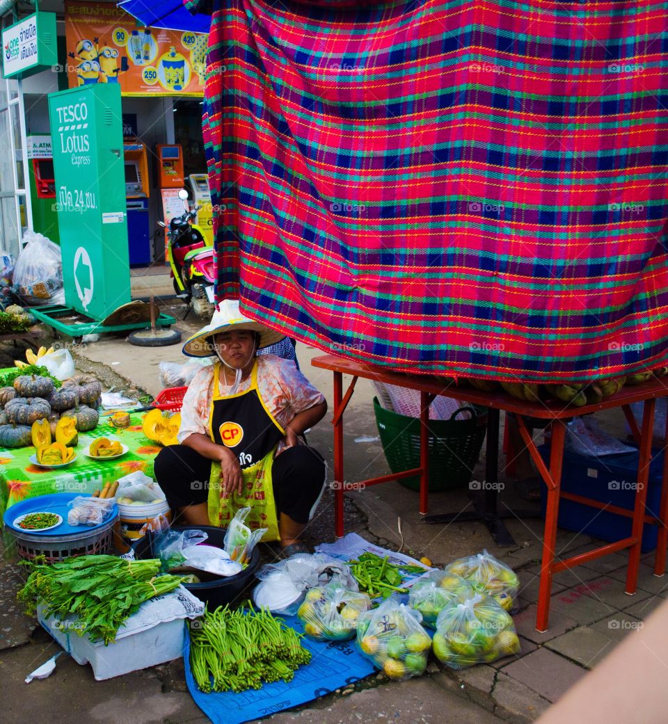 A local woman sells her fresh produce at an outdoor market in Chang Rai, Thailand.