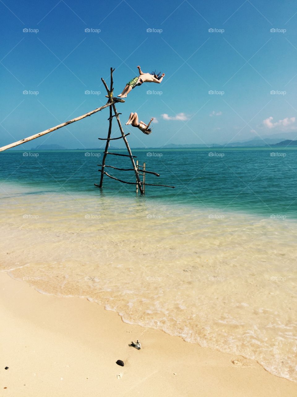 Man and woman jump off into tropical paradise