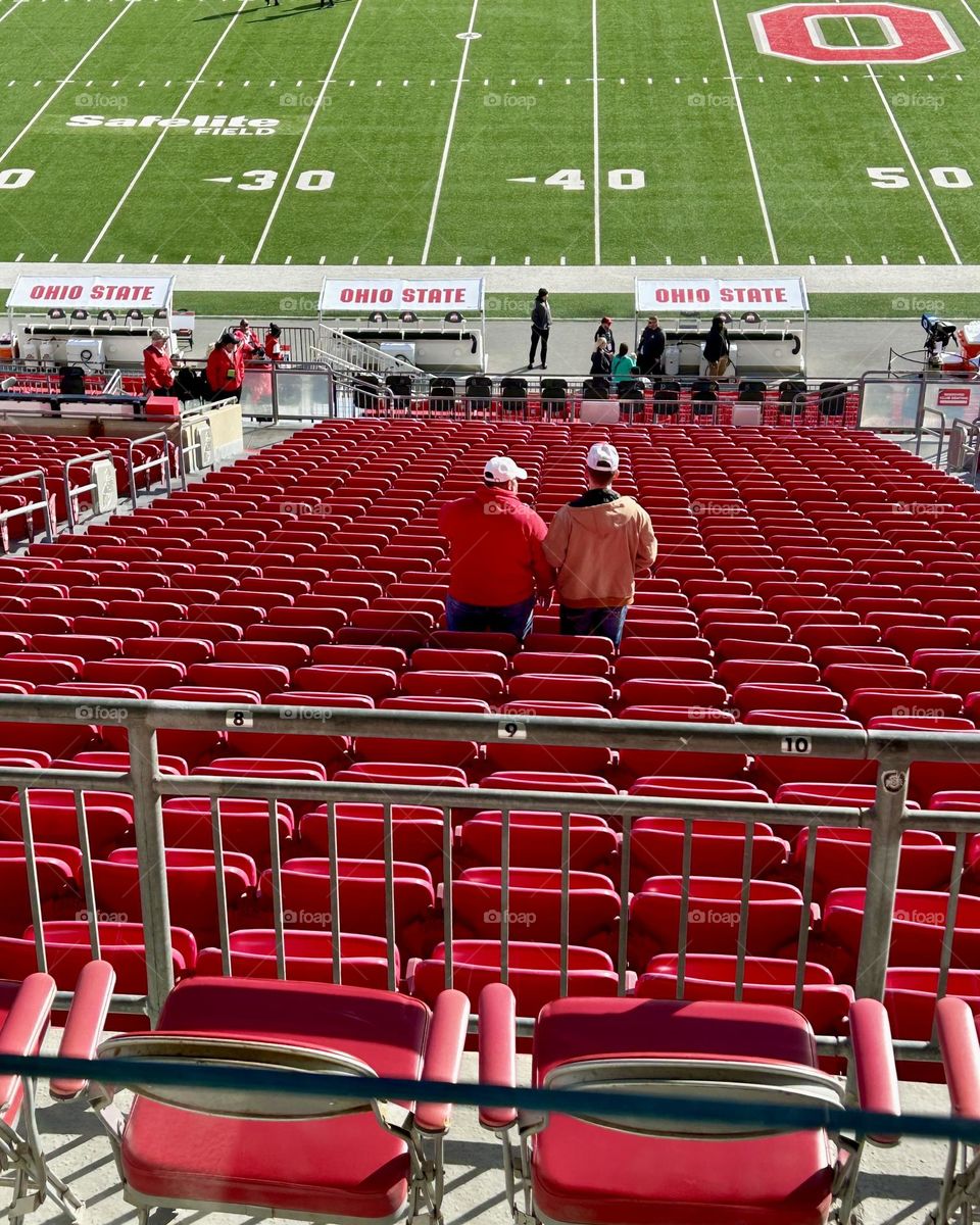 Two men in a football stadium waiting on the game to start