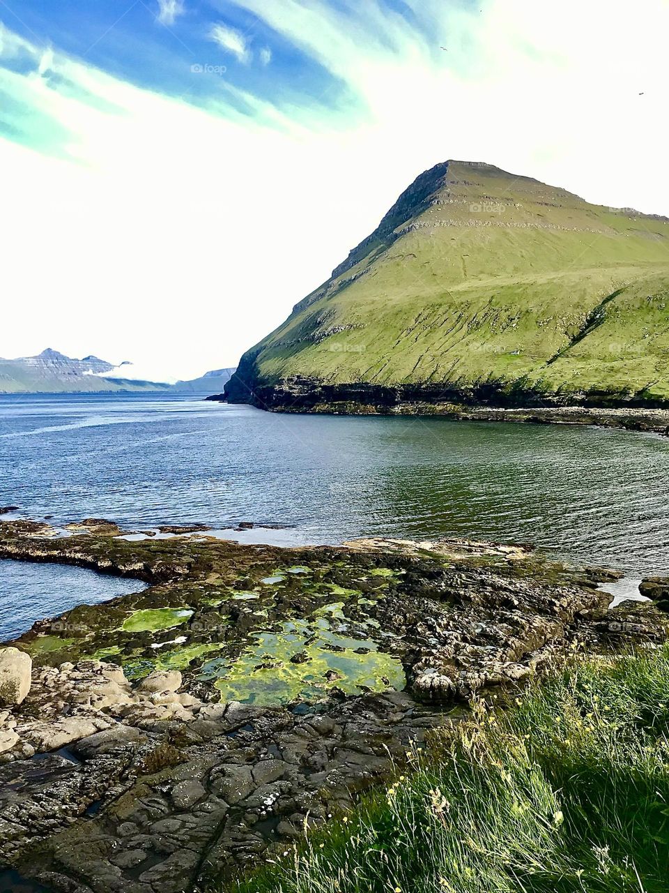 Green mountain rising from freezing cold sea in the Faroe Islands 