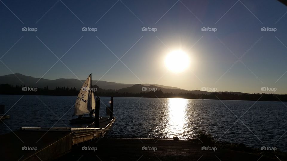 high contrast afternoon sailboat, docking at lake