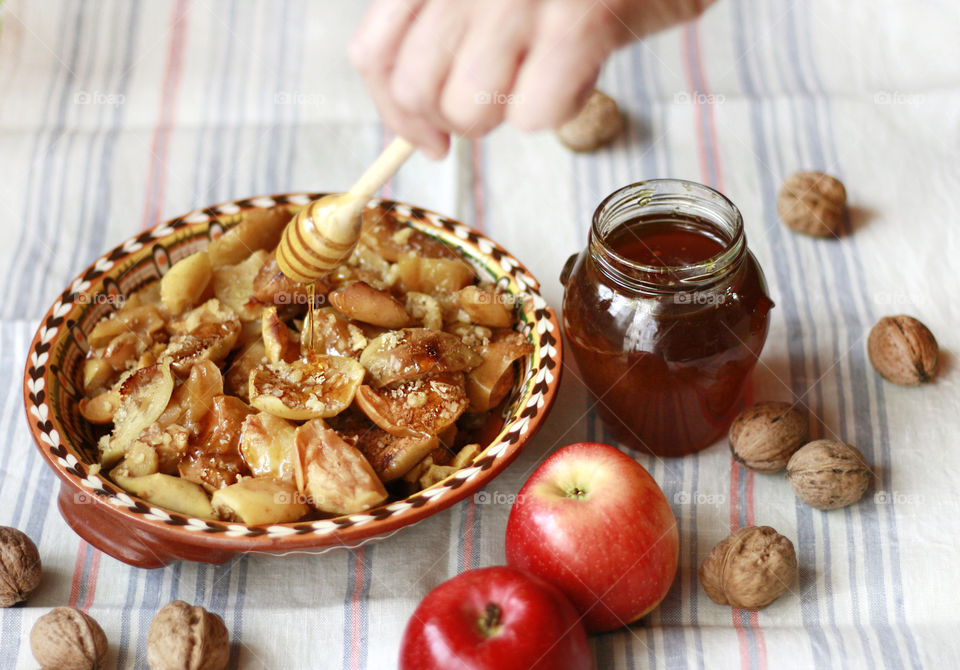 Baked appkes in the rustic plate on the table, honey in the jar