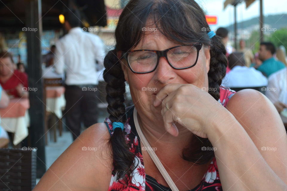 Close-up of a woman laughing covering her mouth with a hands