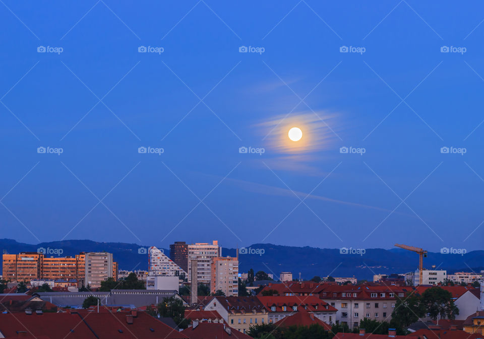 Full moon above my city. Full moon on bright blue sky after sunset above the city of Ljubljana, Slovenia