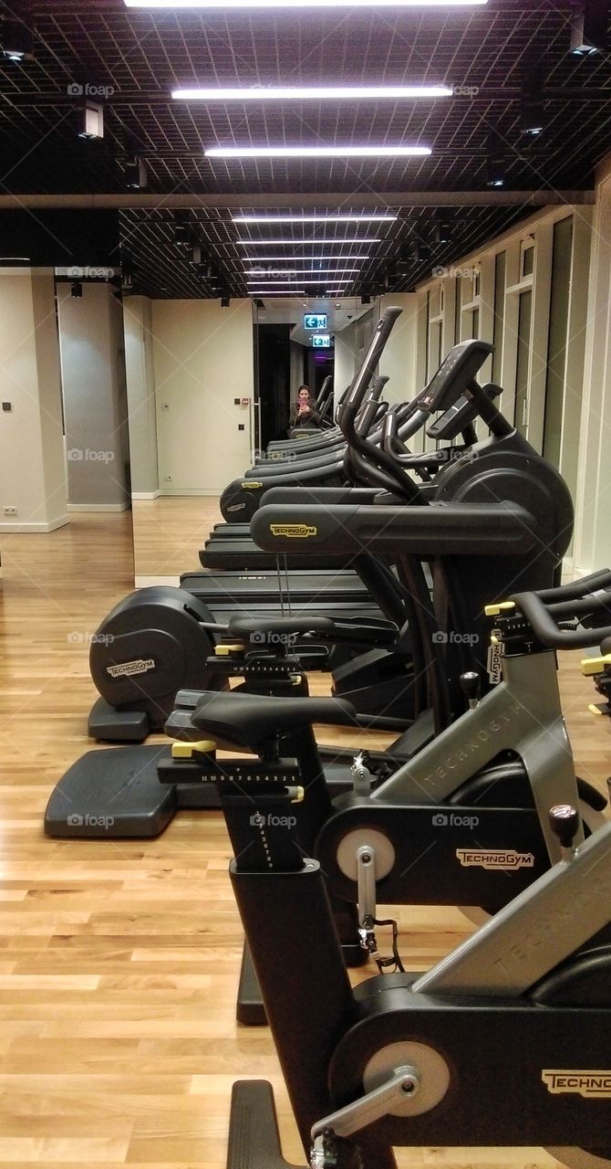 Woman with smartphone taking mirror selfie in gym