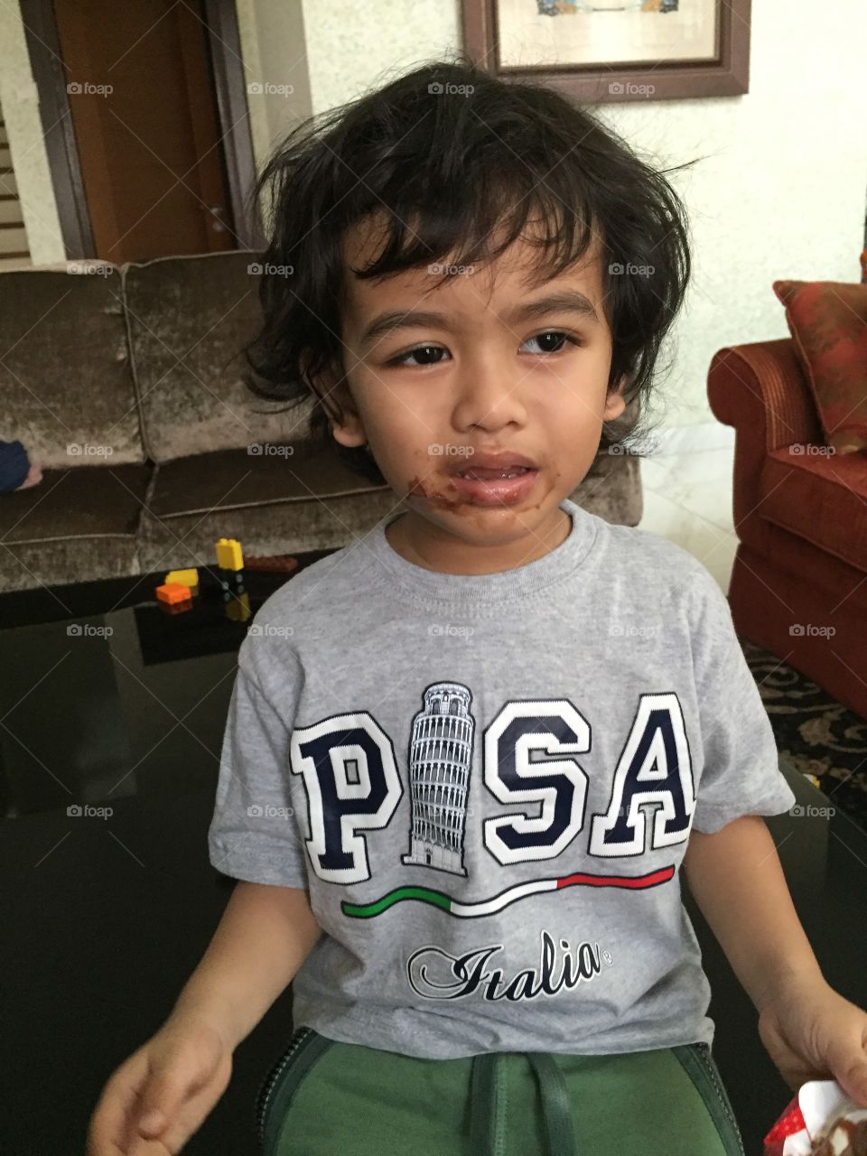 Little boy grumpy and upset got chocolate all over his face 