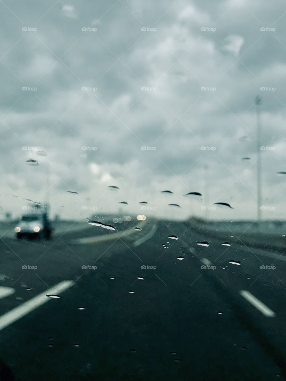 Stormy sky over highway. Roadway not in focus. Raindrops on the windshield are in focus giving an abstract look to the shot. Leaving the jersey shore