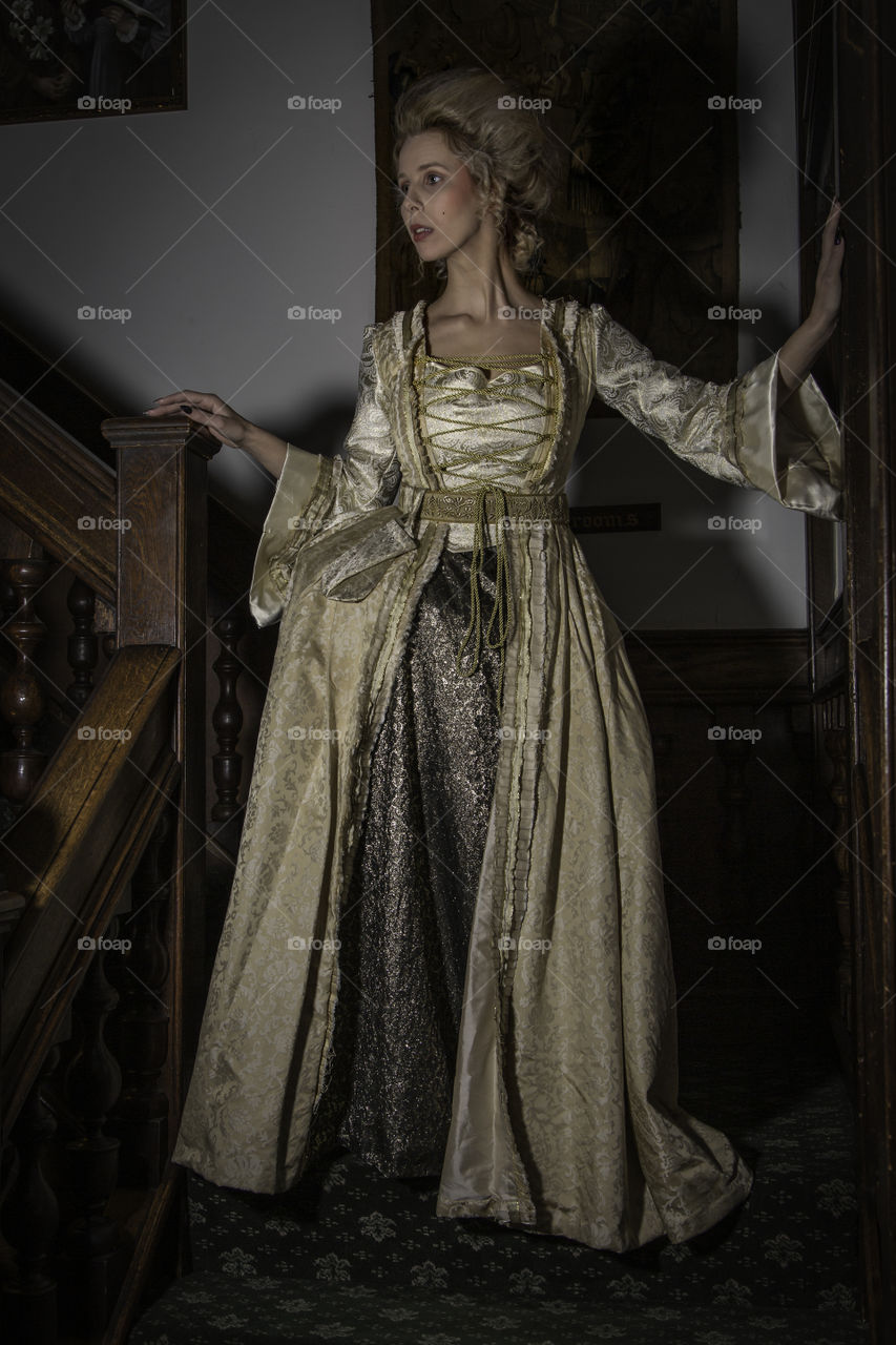 One of a set of photos taken in a 17th century house that is now a restaurant and hotel. The look is based around Marie Antoinette with long luxurious dress and hair styled high. Makeup was very pale and finished using baby powder