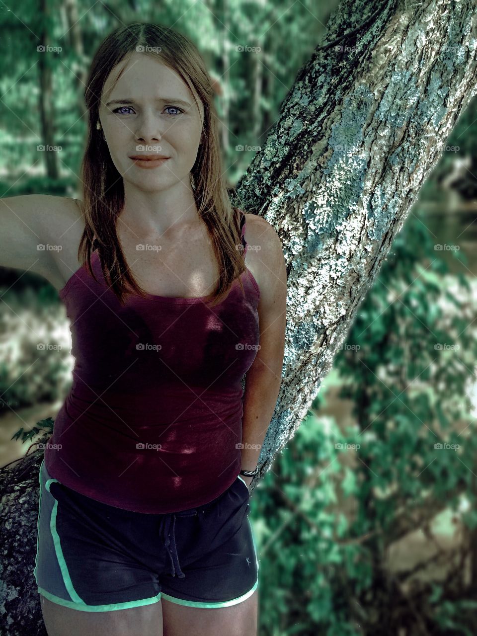 Sad teenage girl standing in front of tree