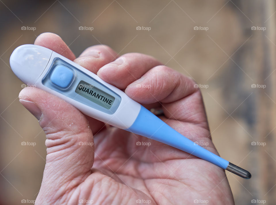 Male hand holds clinical thermometer with covid-19 text on the screen during global covid-19 or corona pandemic.