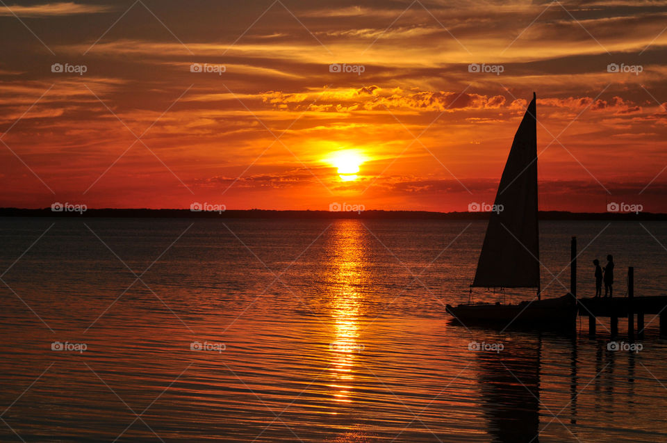 Sailboat moored on pier at sunset