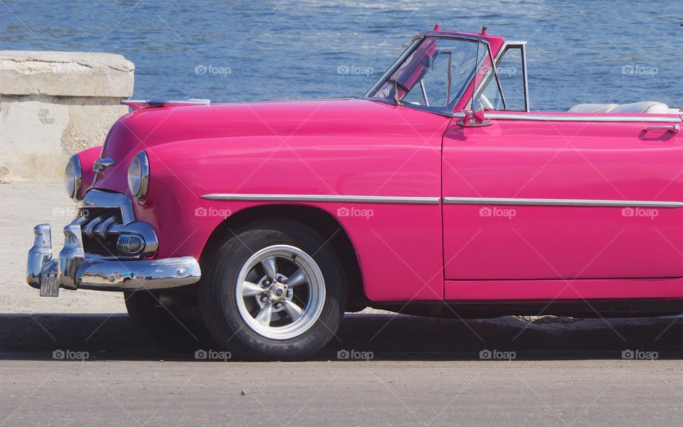 A classic American pink convertible car parked on the famous Malecon Avenue in Havana, Cuba 