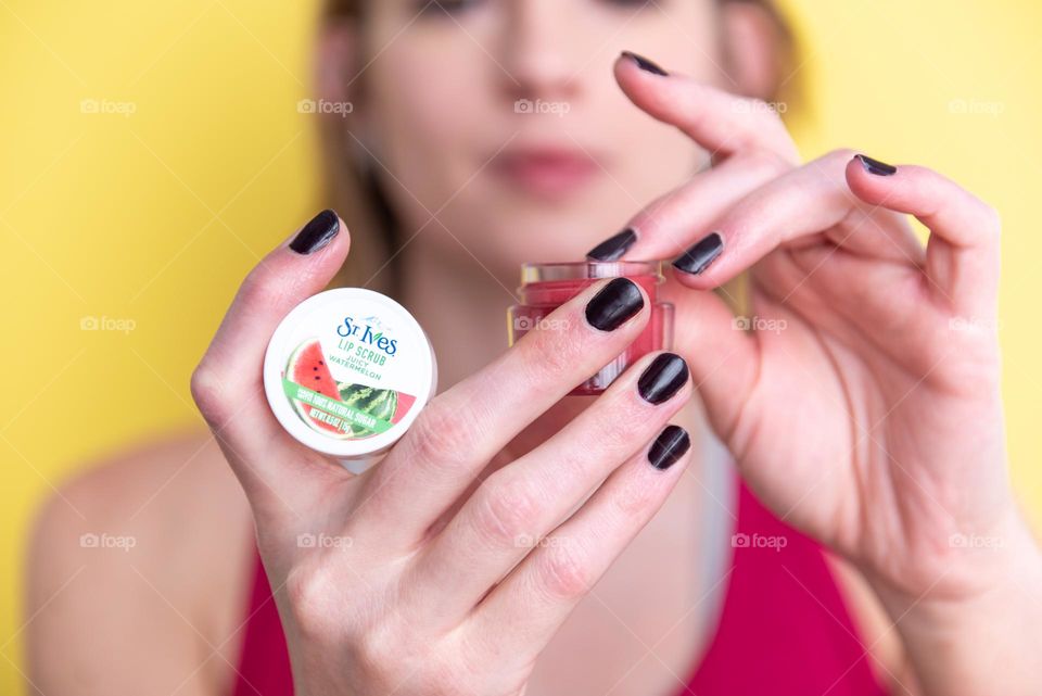 Woman with painted nails applying a lip scrub