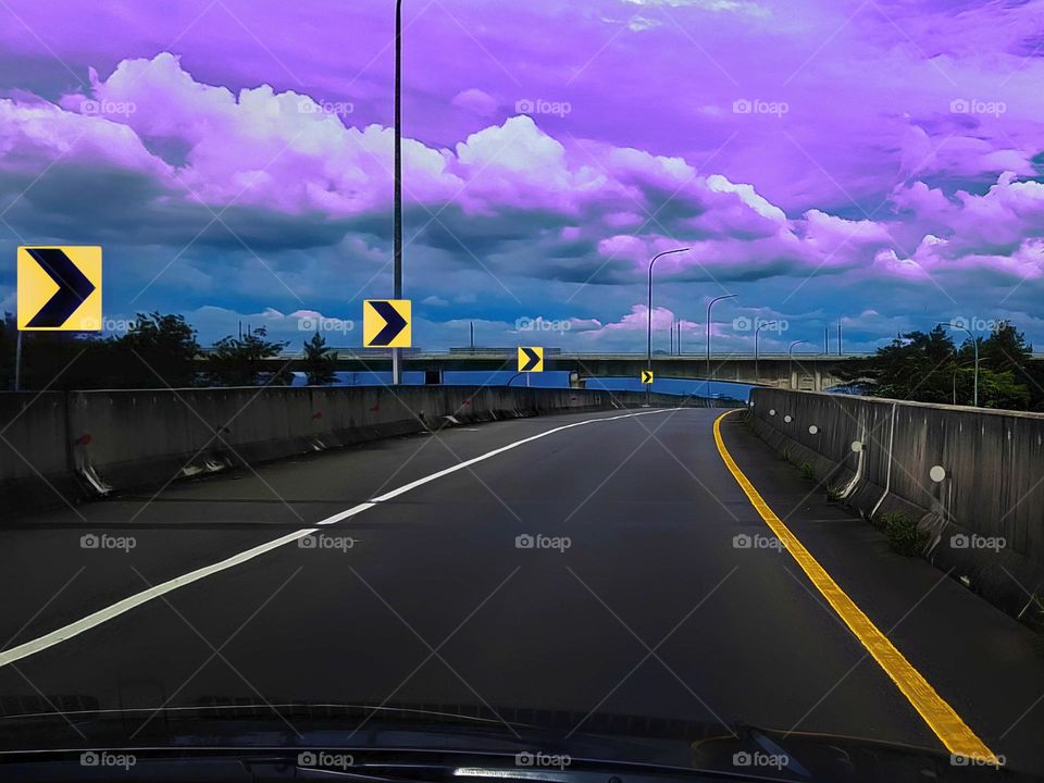 Drivig on the toll road, traffic sign, turn right, warning signs, chevron traffic signs, thhis traffic sign is repeated, the view of the toll road is very beautiful, white and dark clouds, purple blue sky, beautiful illustratnatural outdoor scenery,