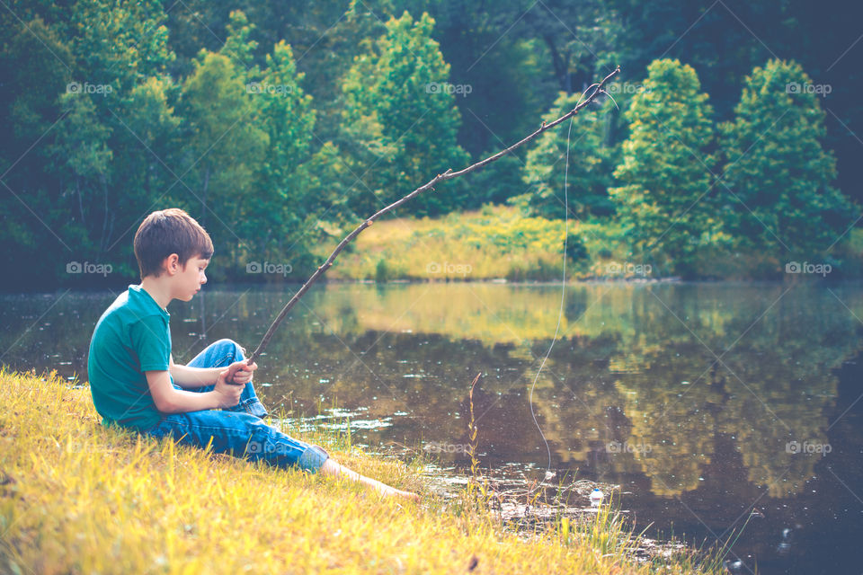 Young Boy Fishing at a Pond with Stick Pole