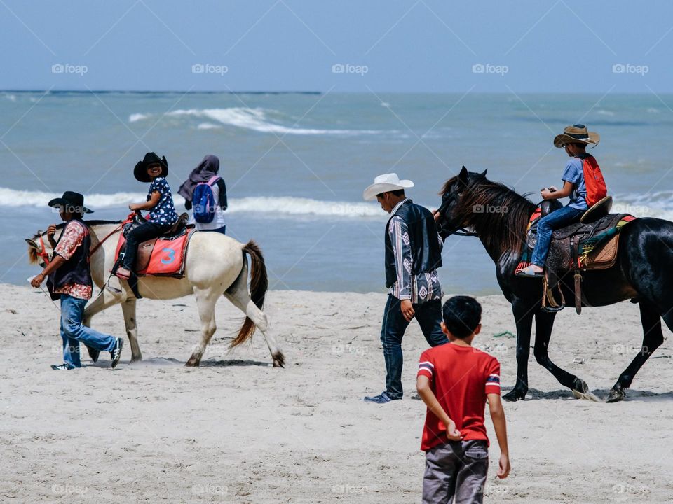 A group of children riding horses on the beach of Songkla, Thailand