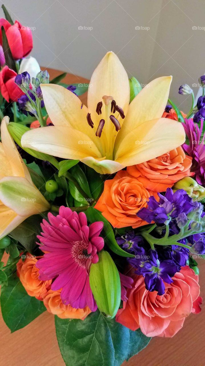 A colorful spring bouquet featuring orange roses and a lily