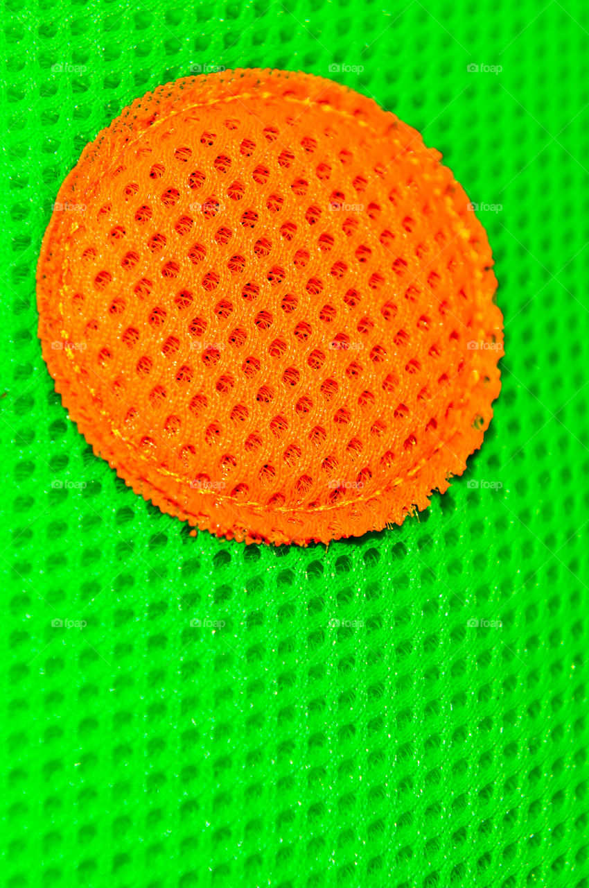 Bright green porous texture with textured orange circle